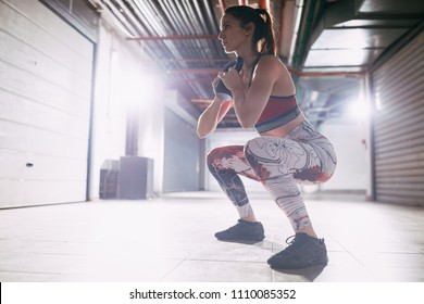 Young Muscular Woman Exercise Goblet Squat With Kettlebell On Hard Training At The Garage Gym.