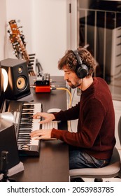 Young Music Producer Wearing Headphones Recording Music With Electric Piano At Home Music Studio