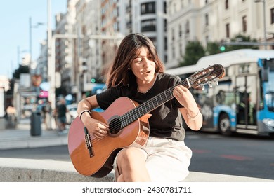 young music student sitting in the city playing the acoustic guitar. - Powered by Shutterstock