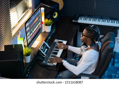 Young Musician Of African Ethnicity Sitting In Studio Of Recording, Making New Music And Mixing Sounds In Computer