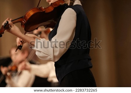 A young musician playing the violin in an orchestra a girl with a musical instrument close up
