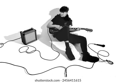 Young musician sitting on the floor with a guitar. White background.  - Powered by Shutterstock