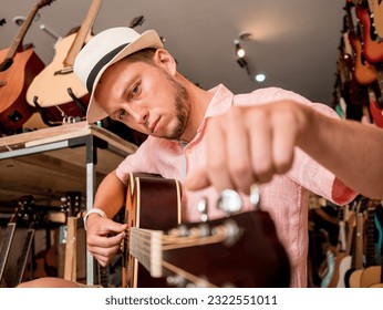 Young musician tuning a classical guitar in a guitar shop