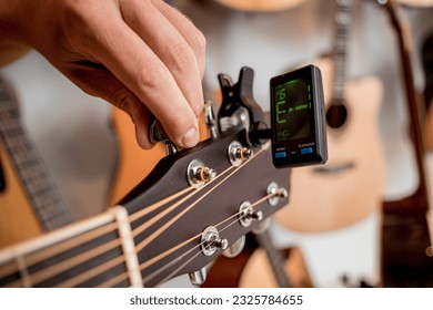 Young musician tuning a classical guitar in a guitar shop - Shutterstock ID 2325784655