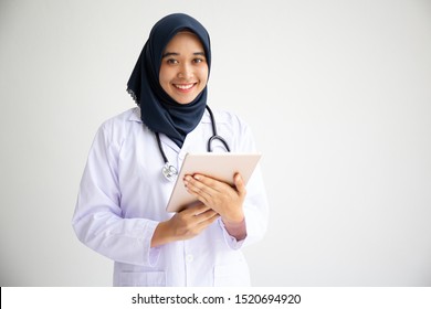 Young Muslim Arab Person Doctor Woman Face On Isolate White Background Concept Islamic Healthcare In Tech Research Hospital Health Medic Care, Indonesian Asian Nurse Worker Hijab Hold Tablet Ipad.