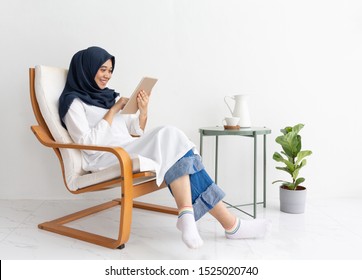 Young Muslim Indonesia Asian Woman Happy On Tablet Casual Home Chair. Malay Lady Journalist Sit Hijab Girl Islam Business On Phone Smartphone Mobile Online. Ramadan Malaysia Family Video Call Isolate.