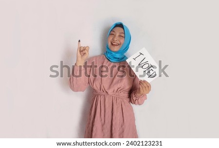 Young muslim student college girl showing paper with text I Voted and finger after voting on Indonesia presidential election