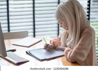 Young Muslim  Student Writing And Working In Traditional Clothes.