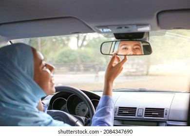 Young Muslim Woman Adjusting Rear View Mirror In Car