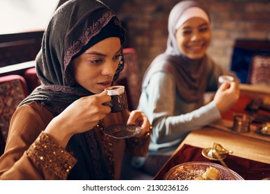 Young Muslim Woman Drinking Coffee While Eating Dessert With Her Friends At Home. 