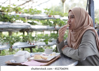 Young Muslim Woman Eating Delicious Scone With Strawberry Jam And Tea At The Strawberry Farm 