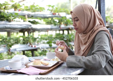 Young Muslim Woman Eating Delicious Scone With Strawberry Jam And Tea At The Strawberry Farm 