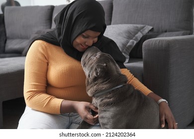 Young muslim woman hugging her grey sharpei dog at home. Love for animals concept. - Powered by Shutterstock