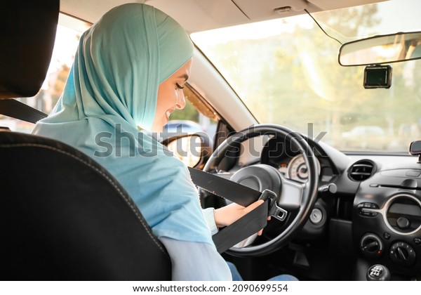 Young Muslim woman in modern\
car