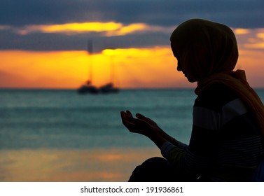 Young muslim woman praying at sunset 