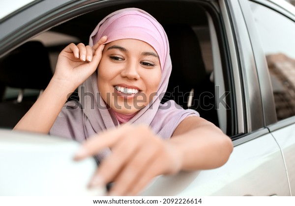 Young Muslim woman sitting in\
car