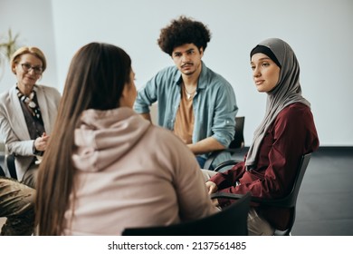 Young Muslim Woman Talking To Group Therapy Members During Their Meeting At Mental Health Center. 