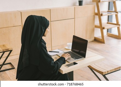 Young Muslim Woman Using Laptop With Blank Screen In Cafe