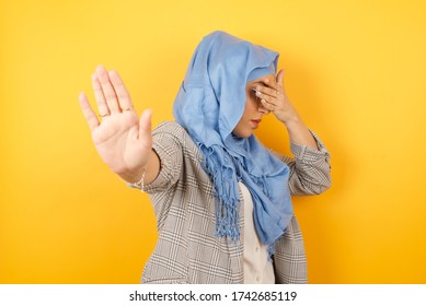 Young Muslim Woman Wearing Hijab Covers Eyes With Palm And Doing Stop Gesture, Tries To Hide From Everybody. Don't Look At Me, I Don't Want To See, Feels Ashamed Or Scared.