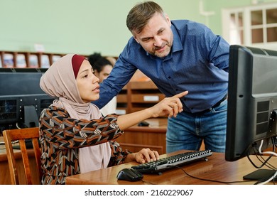 Young Muslim woman wearing hijab doing difficult task on desktop computer asking teacher to help with it - Shutterstock ID 2160229067