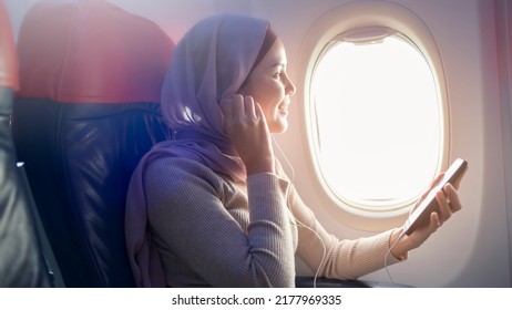 A Young Muslim Woman Wearing Hijab Using Smartphone Onboard, Travel And Holidays Concept