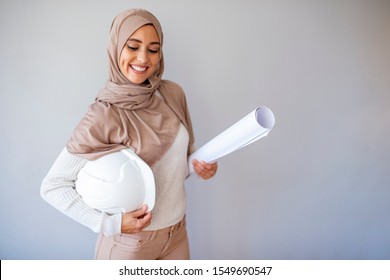 Young Muslim Woman Wearing A Protective Helmet Standing On Gray Background. Portrait Of A Young Muslim Architect-woman Smile. Architect Young Muslim Women At Work. 