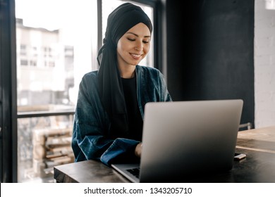 Young Muslim woman working remotely on a laptop sitting in the office