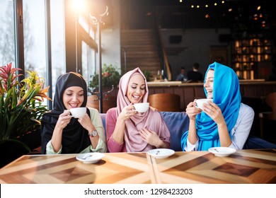 Young Muslim Women Drink Coffee In Cafe With Friends