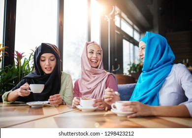 Young Muslim Women Drink Coffee In Cafe With Friends