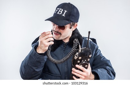 Young mustache FBI agent looking defeated while talking on vintage radio baseball cap