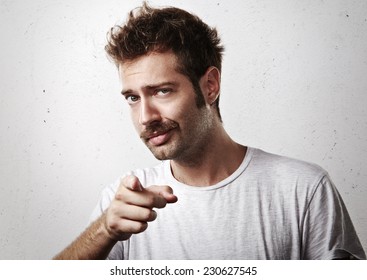 Young mustached man pointing towards the camera
