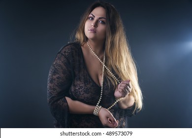 Young naked beautiful caucasian plus size model, xxl woman in black peignoir on smoky studio background, beauty female nude body with big breast