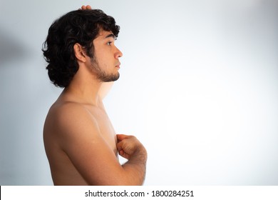 Young Naked Hispanic Man With Wavy Hair And Shaved Beard, Doing A Checkup On His Chest For Signs Of Breast Cancer