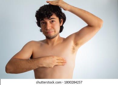 Young Naked Hispanic Man With Wavy Hair And Shaved Beard, Doing A Checkup On His Chest For Signs Of Breast Cancer