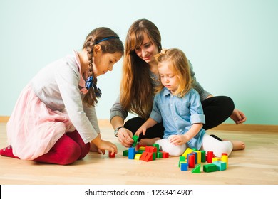 Young nanny playing with kids while babysitting