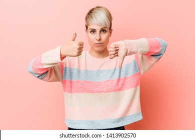Young natural curvy woman showing thumbs up and thumbs down, difficult choose concept