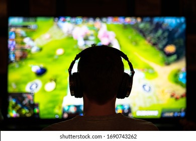 Young Nerdy Adolescent Esport Gamer Playing And Winning Competitive Internet MMORPG Cyber Championship In First Person Shooter Strategy Online Video Game Wearing Headphones On Computer Gaming Rig