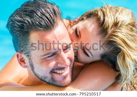 Young newly in love couple enjoys the time together while bathing in the pool