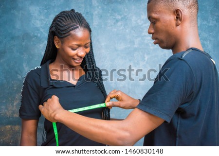 a young Nigerian tailor taking measurement of his client breast 