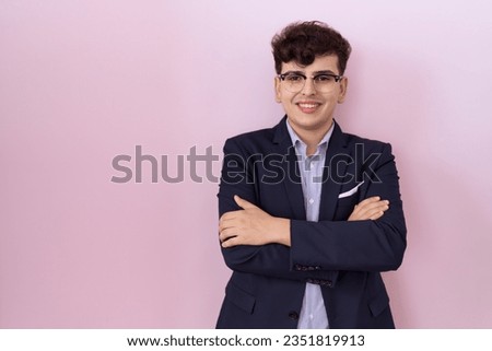 Young non binary man with beard wearing suit and tie happy face smiling with crossed arms looking at the camera. positive person. 