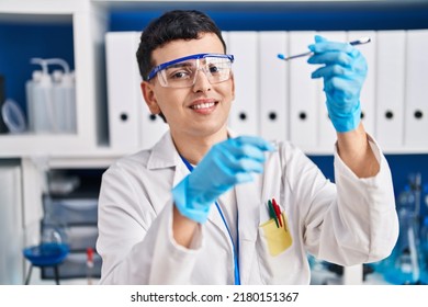 Young Non Binary Man Scientist Smiling Confident Holding Pills At Laboratory