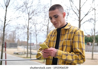 Young non binary person checking his smartphone and smiling. Make up androgynous person. - Powered by Shutterstock