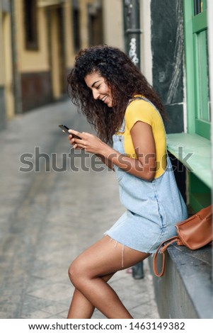 Similar – Frau mit Afro-Haaren auf der Straße, die ein Smartphone hält.