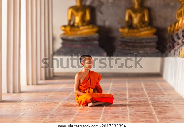 Young novice monk sitting for\
meditation at Wat Phutthaisawan temple, Ayutthaya,\
Thailand