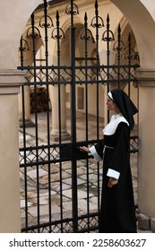 Young nun in cassock near metal door outdoors - Shutterstock ID 2258603627