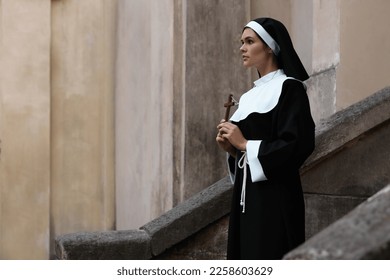 Young nun with Christian cross near building outdoors - Shutterstock ID 2258603629