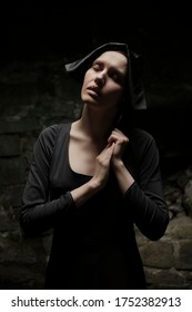 Young Nun Girl Inside Dark Church. Dusk Room Without Candles. Portrait Of A Humble Person. Closed Eyes.