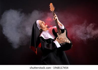Young nun playing guitar on dark background