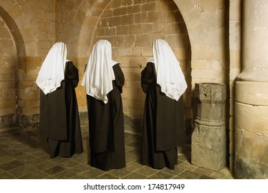 Young nuns facing the walls of a 14th century medieval abbey