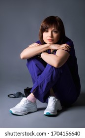 Young Nurse In Blue Work Clothes Posing On A Gray Background During A Photo Shoot.